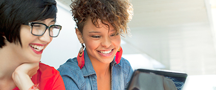 Deux femmes entrepreneures assises devant un ordinateur portable sourient en regardant un courriel.